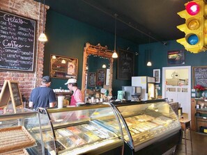 Eine Bäckerei mit einer Glastheke voller Gebäck und einer Kreidetafel, die Artikel wie Gelato und Kaffee auflistet.