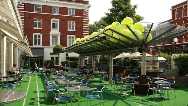 An outdoor cafe with tables and chairs, a covered seating area, and a building in the background. - Spacious, baby-ready 2br 1st floor in Chelsea (london)