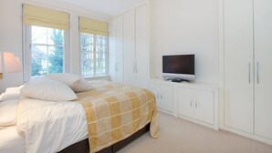 A bedroom with a bed, a television on a stand, and white cabinets. - Spacious, baby-ready 2br 1st floor in Chelsea (london)