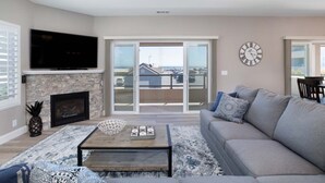 Un salon avec une cheminée, un téléviseur à écran plat, un canapé et un balcon avec vue.