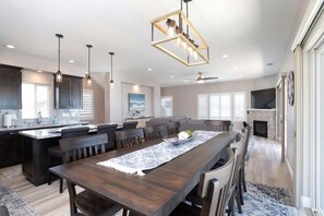 A spacious kitchen with a central island, pendant lighting, and a dining area with a long table.
