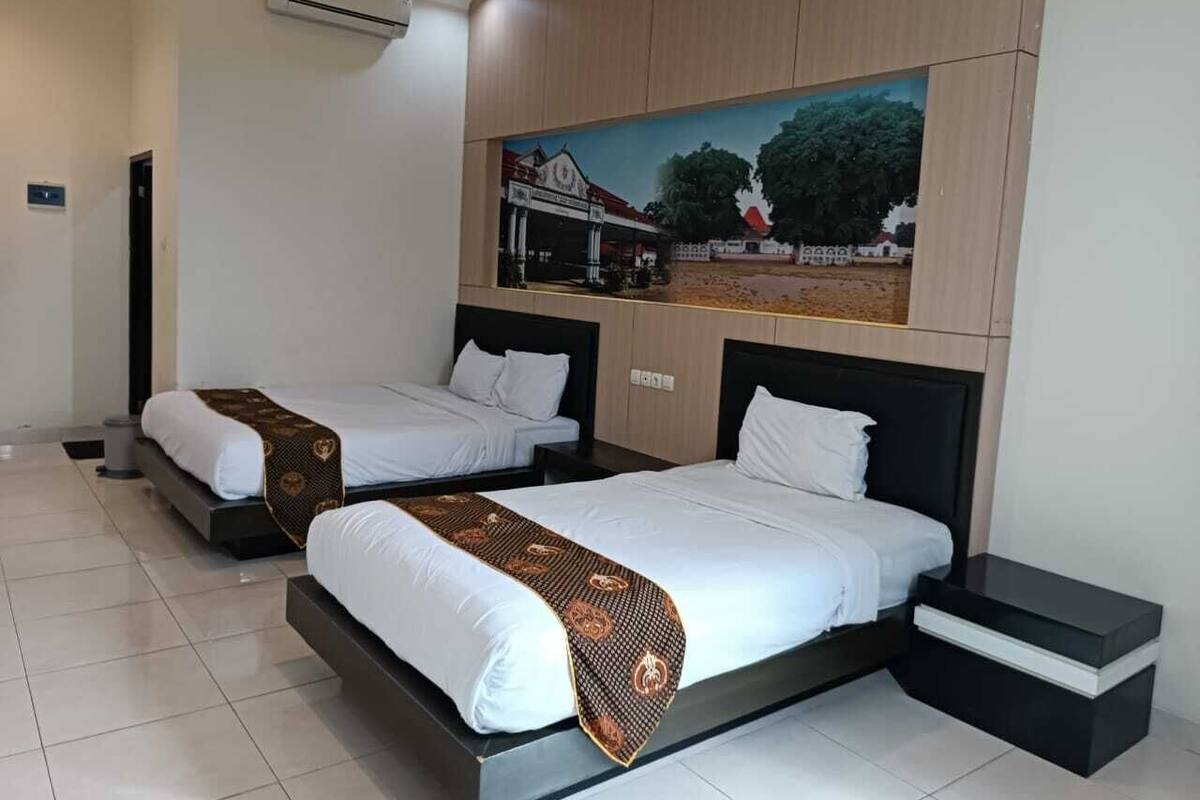 A hotel room with two single beds, a large painting on the wall, and a tiled floor.