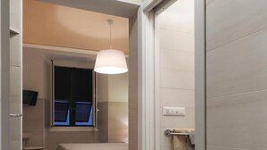 Un dormitorio moderno con cama, mesita de noche y lámpara colgante.