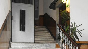 Una escalera de mármol con barandilla de metal que conduce a una puerta con teclado de seguridad.