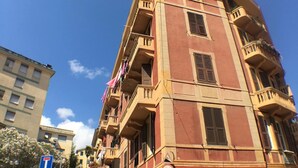 Un edificio de varios pisos con balcones, una entrada visible en la planta baja y un cielo despejado.