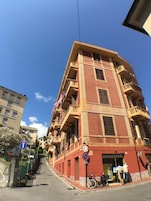 Un edificio a più piani con balconi, un ingresso al piano terra ben visibile e un cielo sereno.