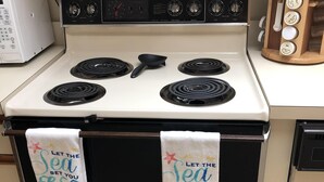 A kitchen with a white stove, black oven, and a wooden cutting board. - Cozy Condo on the water (Dunnellon)