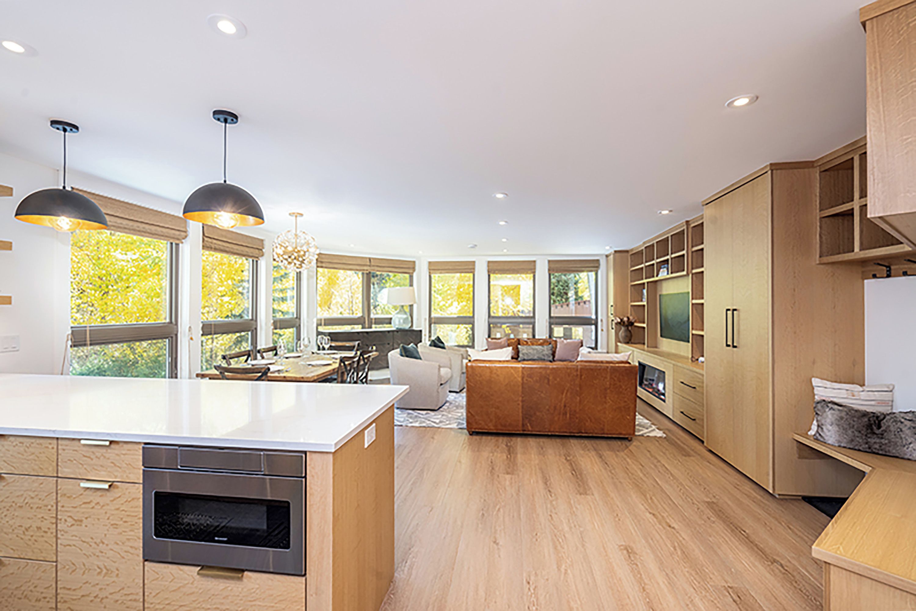 A modern kitchen with a central island, built-in appliances, and a dining area with a view.