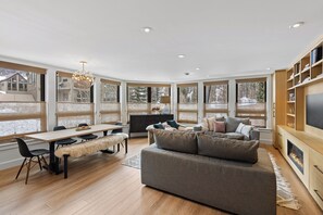 Un salon moderne doté d’une cheminée, de grandes fenêtres et d’un coin salon confortable.