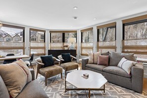Un salon spacieux doté d’une grande fenêtre, d’une cheminée et d’un coin salon confortable.