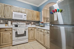 Kitchen features a refrigerator, microwave, oven, and various kitchen utensils and appliances.