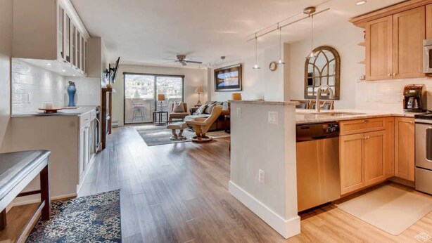 A modern kitchen with wooden cabinets, a dishwasher, and a large window.