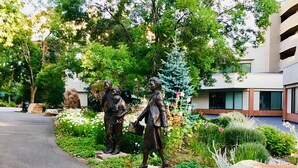 A garden with statues, a paved walkway, and a building in the background.