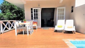 An outdoor pool area with a wooden deck, a dining table with chairs, and two lounge chairs. - Sugar Fields Hoilday Home with Private Pool. (Valley Church)