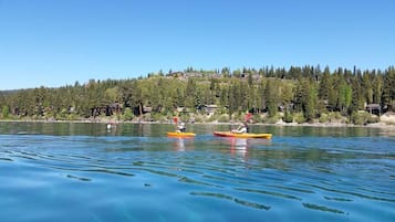 Un lac paisible où l’on peut faire du kayak, entouré d’une colline boisée et de quelques maisons.
