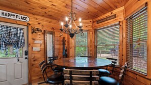A wooden interior with a round table and chairs, a chandelier, and a sign that reads 'HAPPY PLACE'. - Drink Up The View - Morganton (Morganton)