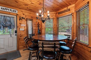 A wooden interior with a round table and chairs, a chandelier, and a sign that reads 'HAPPY PLACE'. - Drink Up The View - Morganton (Morganton)