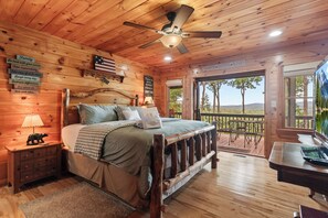 A wooden cabin bedroom with a bed, nightstands, a lamp, and a view of the outdoors. - Drink Up The View - Morganton (Morganton)