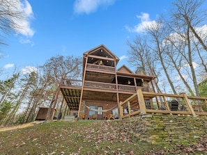 A multi-level wooden cabin with a stone foundation, surrounded by trees. - Drink Up The View - Morganton (Morganton)
