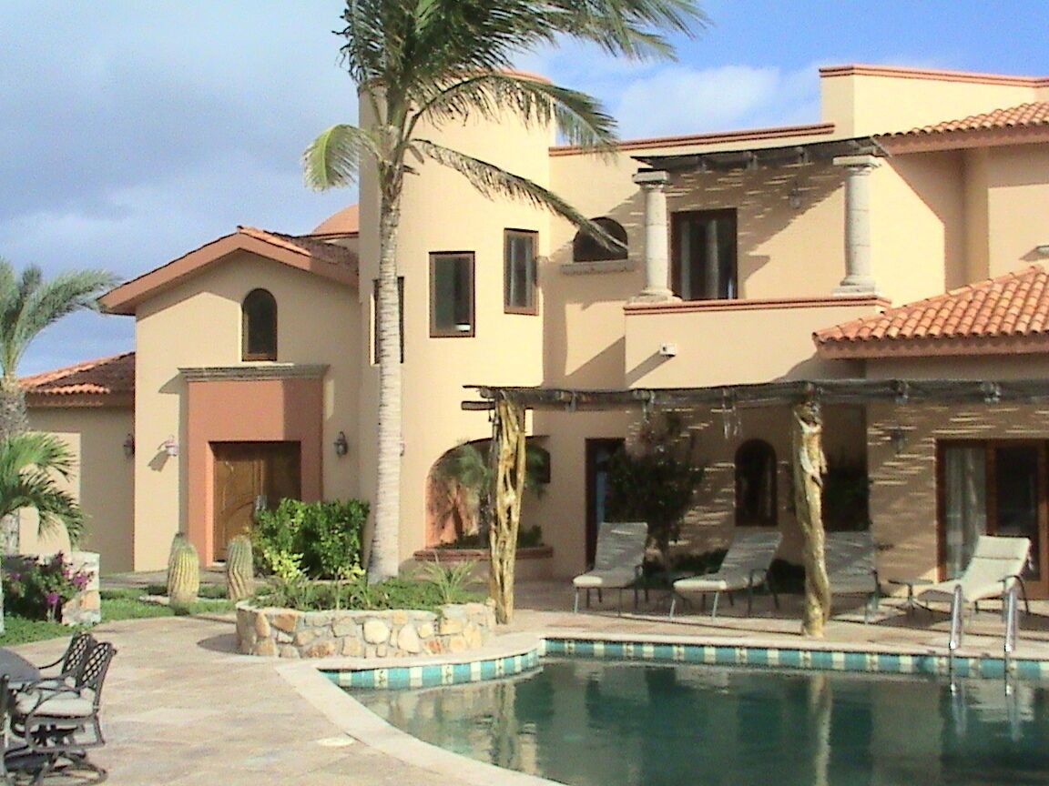 Un bâtiment à deux étages doté d’une piscine, de palmiers et de chaises longues.