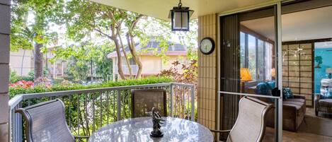 A balcony with a round table, two chairs, and a hanging lantern.