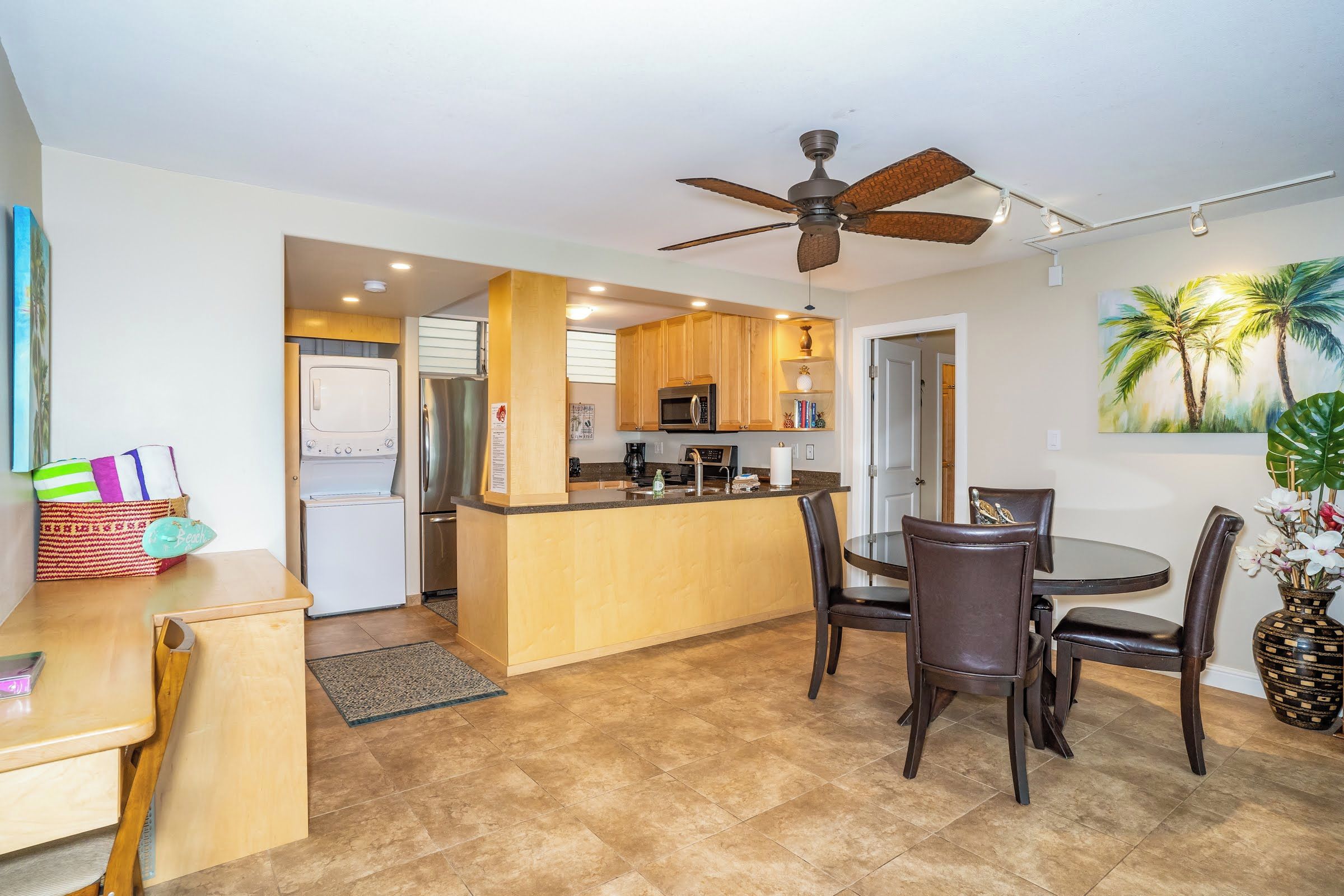 A compact kitchen with a central island, wooden cabinets, and a ceiling fan.