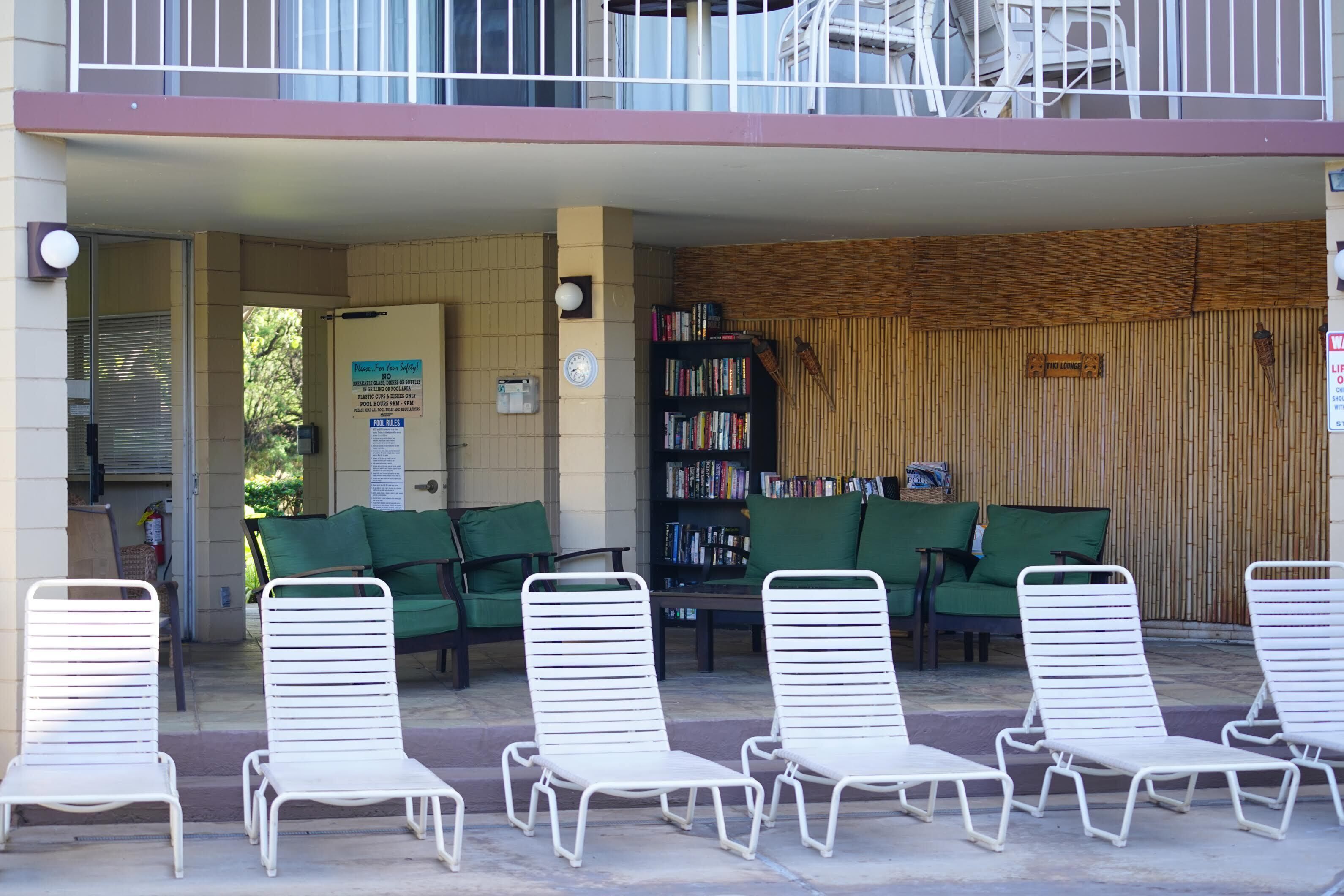 Ein überdachter Außenbereich mit weißen Lounge-Stühlen und einem Bücherregal voller Bücher.