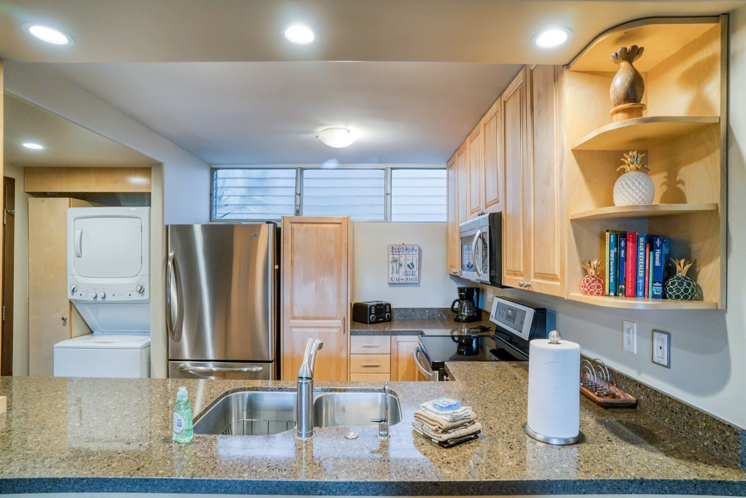 A modern kitchen with stainless steel appliances, granite countertops, wooden cabinets, and a microwave.