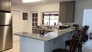 Una cocina moderna con encimeras de granito, electrodomésticos de acero inoxidable y armarios de madera.