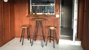 Un interior de madera con una ventana, dos taburetes y una puerta.