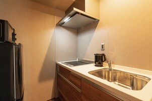 Uma cozinha compacta com pia de aço inoxidável, fogão embutido e micro-ondas.