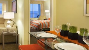 Une chambre d’hôtel avec un lit, une table à manger dressée pour deux personnes et une vue sur le balcon.