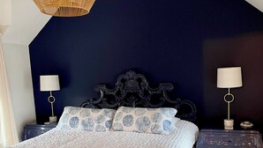 A bedroom with a large bed, dark blue walls, and a ceiling fan. - Cottage in Heart of Downtown Newport (Newport)