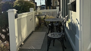 A balcony with a white picket fence, two tables, and chairs. - Cottage in Heart of Downtown Newport (Newport)