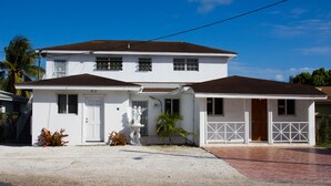 Una casa blanca de dos pisos con techo marrón, un porche delantero y un garaje.