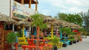 Un restaurante frente a la playa con terraza y sombrillas de paja.