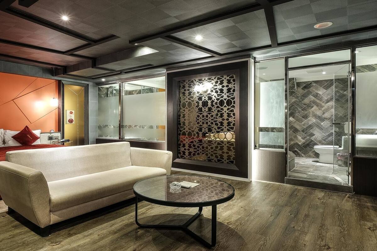 A modern hotel room with a sofa, a round coffee table, and a decorative partition.