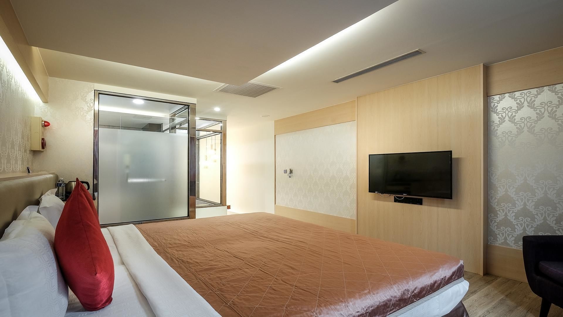 A hotel room with a bed, a TV, a wardrobe, and a shower area.