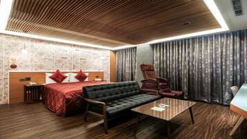 A modern hotel room with a wooden ceiling, a bed with red bedding, a black sofa, a wooden coffee table, and a large window with curtains.