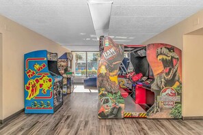 A hallway with arcade machines, including a 'Raw Thrills' game and a 'Jurassic Park Arcade' game.