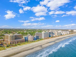 A coastal hotel area with beachfront properties, including multi-story buildings and a sandy beach.