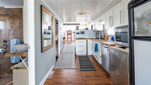 Une cuisine moderne avec des armoires blanches, des appareils en acier inoxydable et un plancher en bois.