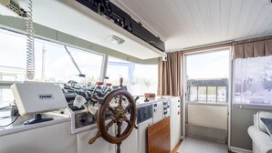 Une cuisine compacte équipée d’un volant en bois, d’un réfrigérateur blanc de la marque ONWA et d’une fenêtre donnant sur l’extérieur.