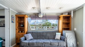 Un salon chaleureux avec un canapé gris, des étagères en bois et une vue par la fenêtre.