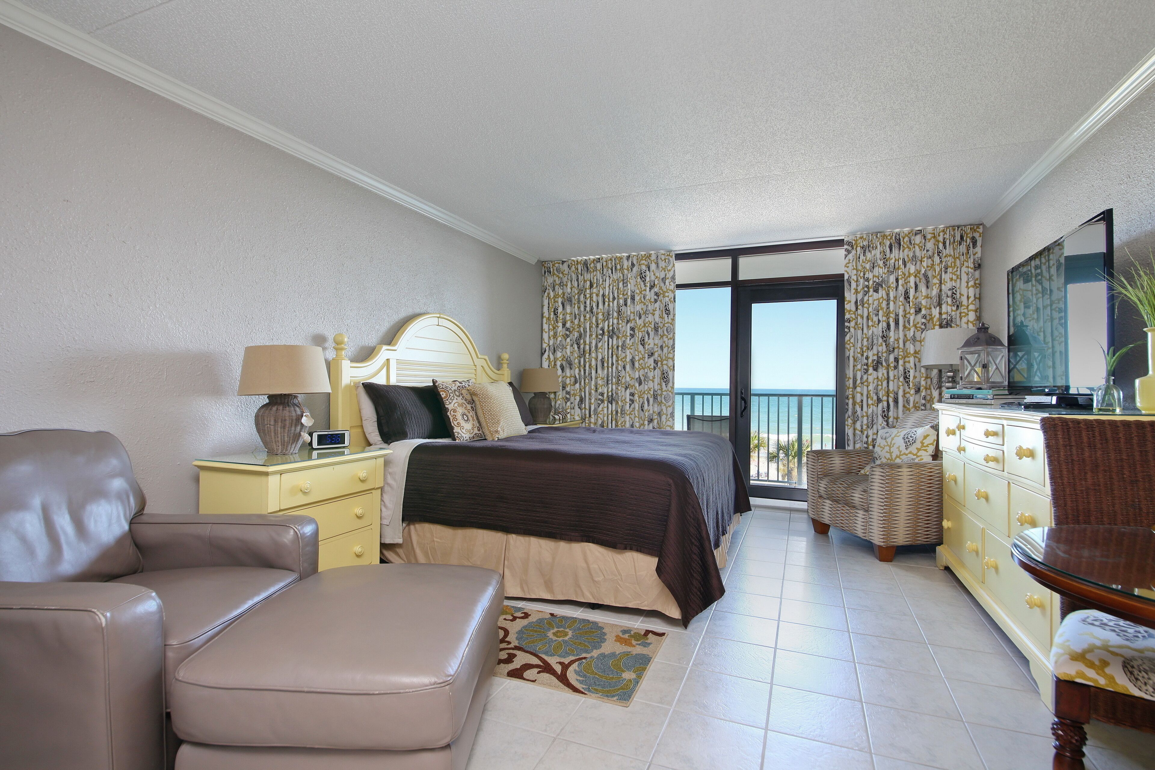 Una habitación de hotel con cama, sofá, cómoda y televisor.