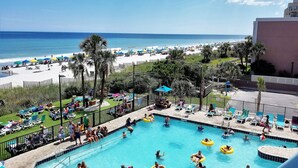 A pool area with a view of the beach, lounge chairs, and umbrellas. - Oceanfront Studio Retreat on the Golden Mile (Myrtle Beach)