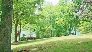 A picnic setup with a basket and blanket in a grassy area with trees. - Mountain Tent Retreat: Game Room Near Ocoee River (Copperhill)