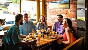 A group of people dining at a restaurant with brick walls and large windows. - Mountain Tent Retreat: Game Room Near Ocoee River (Copperhill)