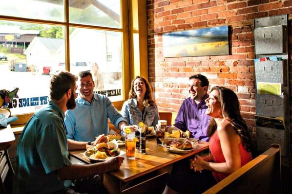 A group of people dining at a restaurant with brick walls and large windows.