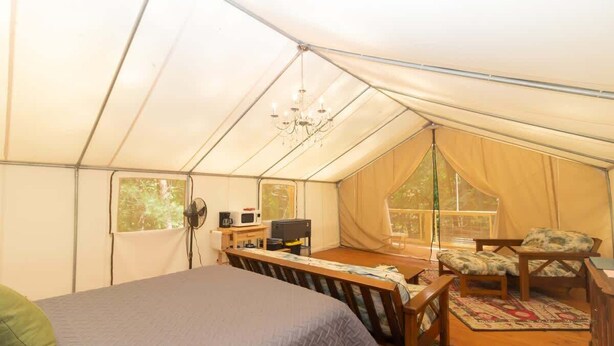 A tent with a bed, a table, chairs, a fan, and a window. - Mountain Tent Retreat: Game Room Near Ocoee River (Copperhill)